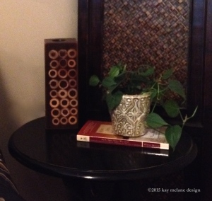 A bedside table with a plant, book and candle makes a peaceful statement in your bedroom. ©2015 kaymclane.com